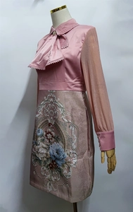Detail view of pink long-sleeved dress featuring intricate floral embroidery on the skirt