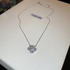 Macro shot of silver clover pendant with sparkling cubic zirconia on a white texture