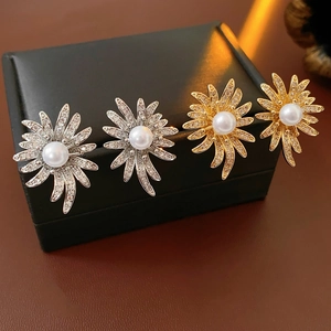Detailed view of sunflower stud earrings with pearls and micro-pave crystals in gold and silver