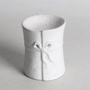 Abstract white ceramic aromatherapy burner with brown spots and molded bow detail