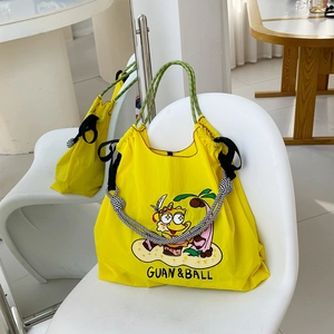 Detail of yellow waterproof nylon tote bag featuring refined cartoon embroidery and thick rope handles