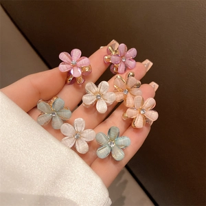 Macro detail of mini pearlescent floral hair claws with rhinestones on gold metal base