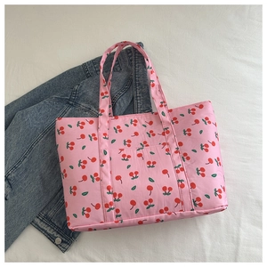 Detailed view of pink cherry print tote bag with double handles and front pocket