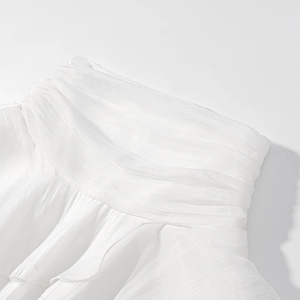 Detailed close-up of white chiffon fabric with elegant pleated textures and smocked design