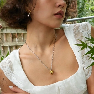 Two-tone heart pendant necklace in silver and gold steel worn by a model