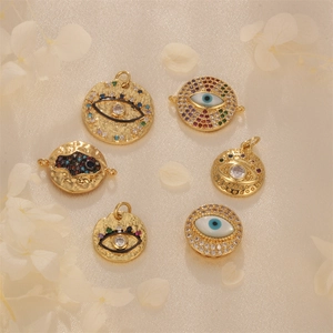 Golden evil eye shell pendants with colorful zircons set on soft white silk fabric