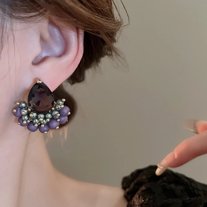 Detail view of purple water drop zircon earrings worn by a model in warm soft lighting