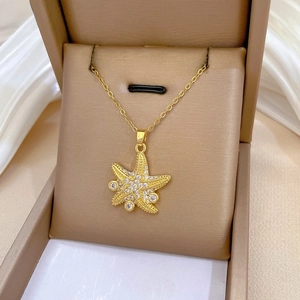 Detailed close-up of a luxury gold starfish necklace with zircon stones in a gift box
