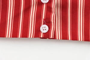 Macro shot of vertical red stripes on cotton fabric with white resin button details