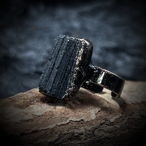 Macro shot of raw black mineral stone set in a metallic adjustable vintage ring band