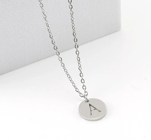 Macro shot of silver titanium steel necklace featuring an engraved letter A round pendant