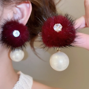 Detail of burgundy fur pom-pom earrings with sparkling zircon and large white pearl drops