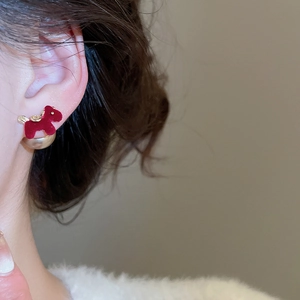 Close-up of red flocked dog stud earrings with large champagne pearl backing on model