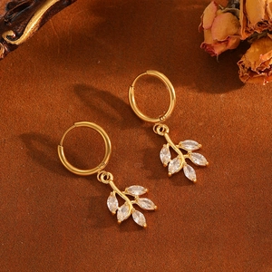 Detail of gold hoop earrings with leaf pendants and sparkling white zircon stones