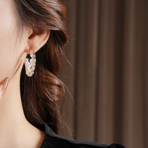 Close-up of textured silver C-shaped hoop earrings with pearls worn by a model