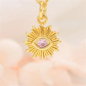 Detail of gold evil eye pendant with pink zircon and sunflower sunburst design