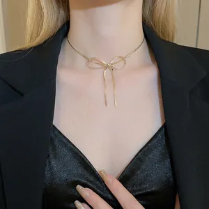 Minimalist gold bow snake chain necklace with tassel pendant worn on female neck