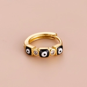 Macro shot of gold hoop earring featuring square evil eye charms and cubic zirconia