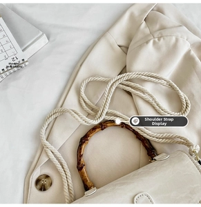 Detail of bamboo handle and woven rope strap on beige minimalist crossbody bag