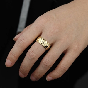 Close-up of golden wave textured ring featuring modern striped metal finish on finger