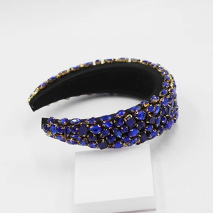 Détail d'un serre-tête baroque avec strass bleu foncé sur base en métal doré brillant