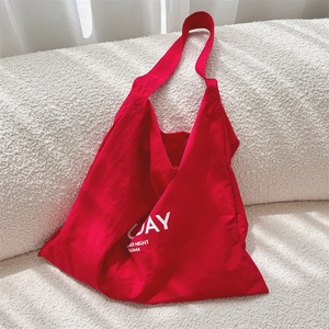 Detail of red canvas tote bag featuring white UAY lettering on a soft white sofa