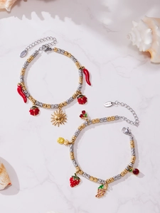 Detail of stainless steel charm bracelets with chili, sun and fruit pendants over marble