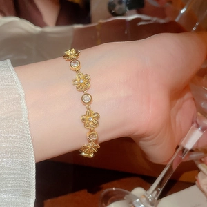 Détail d'un élégant bracelet à fleurs dorées avec zircons au poignet d'une femme