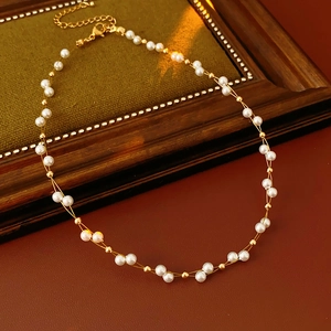 Detailed close-up of double-layer woven pearl and gold bead necklace with lobster clasp