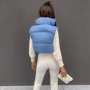 Back view of a cropped bright blue puffer vest with high stand collar and wide quilting