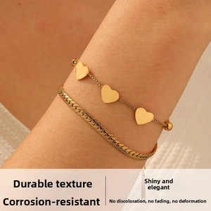 Detail of double-layer gold plated snake chain with heart charms on a female wrist