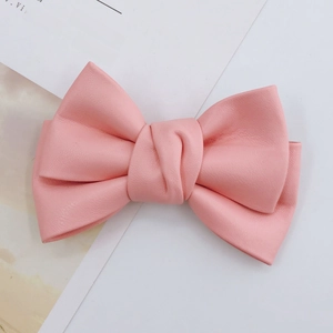 Close-up of pink faux leather bow accessory with realistic texture and knotted center