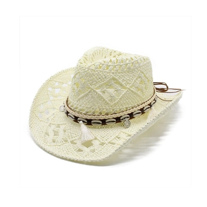 Western hollow-out straw cowboy hat with shell trim and tassels on white background