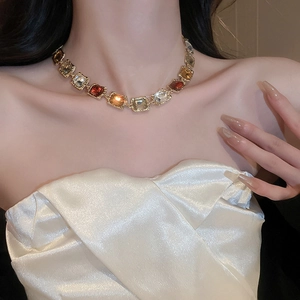 Detail of vintage gold necklace with square amber and brown gemstones on a female model