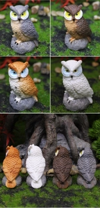Detailed back texture of four resin owl figurines on natural moss and stone base
