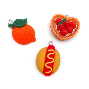 Three DIY resin charms featuring orange, strawberry tart, and hot dog designs on white background