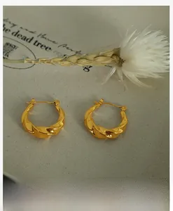 Vue macro de boucles d'oreilles créoles torsadées dorées avec finition 18k polie