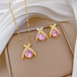 Detailed macro view of pink crystal necklace and earring set on white silk background