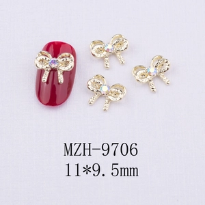 Vue macro d'un nœud doré de 11x9,5mm avec strass pour nail art sur des ongles rouges