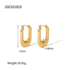 Détail de boucles d'oreilles en U dorées avec surface texturée et hauteur de 2,6 cm