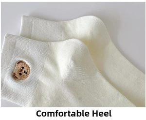 Close-up of white ribbed cotton socks featuring cute brown bear embroidery detail