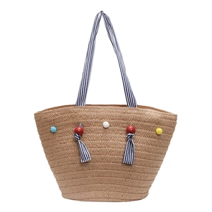 Handwoven straw tote bag with colorful pom-poms and blue striped ribbon handles