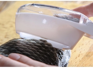 Close-up of hand using the fish scaler tool with cover on a fish on wooden board