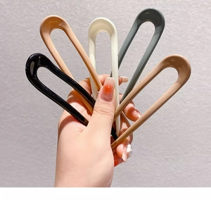 Handheld view of five colorful U-shaped hairpins in glossy plastic for bun styling