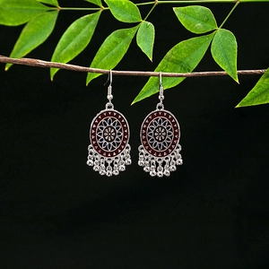 Detail of vintage bohemian silver earrings with red-blue enamel and metallic bead tassels