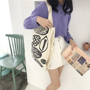 Detail view of off-white canvas tote bag featuring hand-drawn fruit prints on shoulder strap