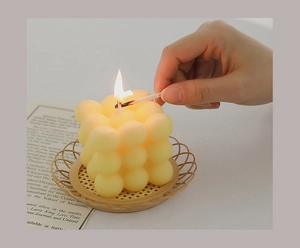 Close-up of lighting a yellow bubble cube scented candle on a bamboo tray