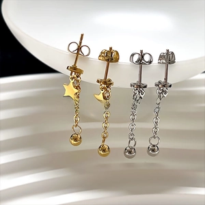 Detail of tassel star and bead drop earrings in gold and silver finish on white ceramic