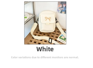 Detail view of white crossbody bag featuring delicate bow embroidery and adjustable strap