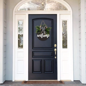 Detail of wooden welcome sign on black door with green plants and checkered bow